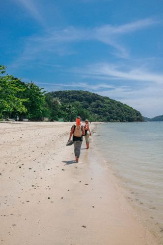 Wandeling met yogamat langs het strand in Phuket